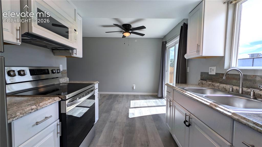 Image 3 of 24: Contemporary kitchen featuring white cabinetry, stainless steel appliances,