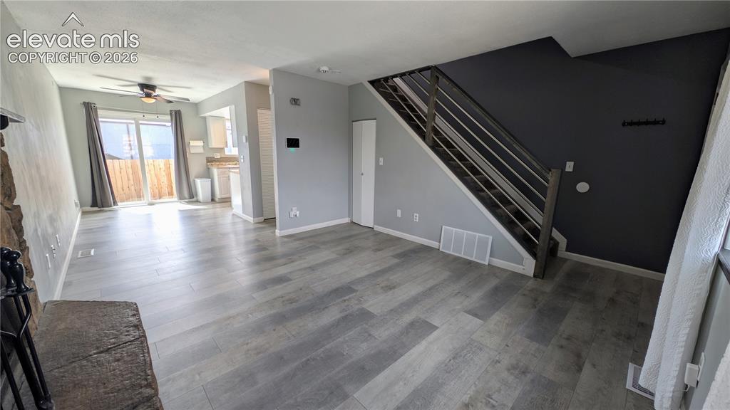 Image 7 of 24: Open-concept living area featuring wood-finish flooring, a stone-clad firep