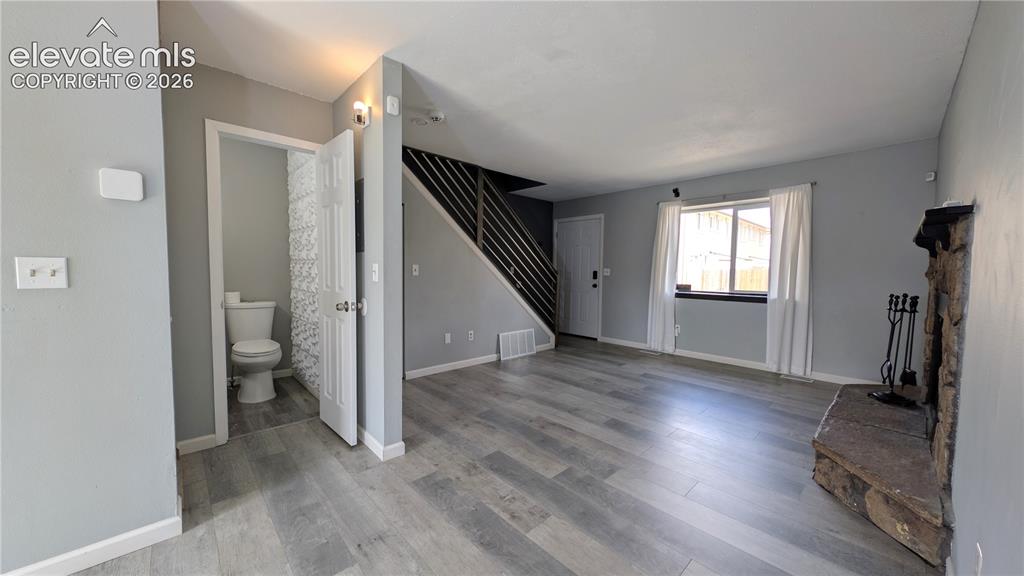 Image 9 of 24: Open concept living area featuring wood-finish flooring, a stone fireplace,