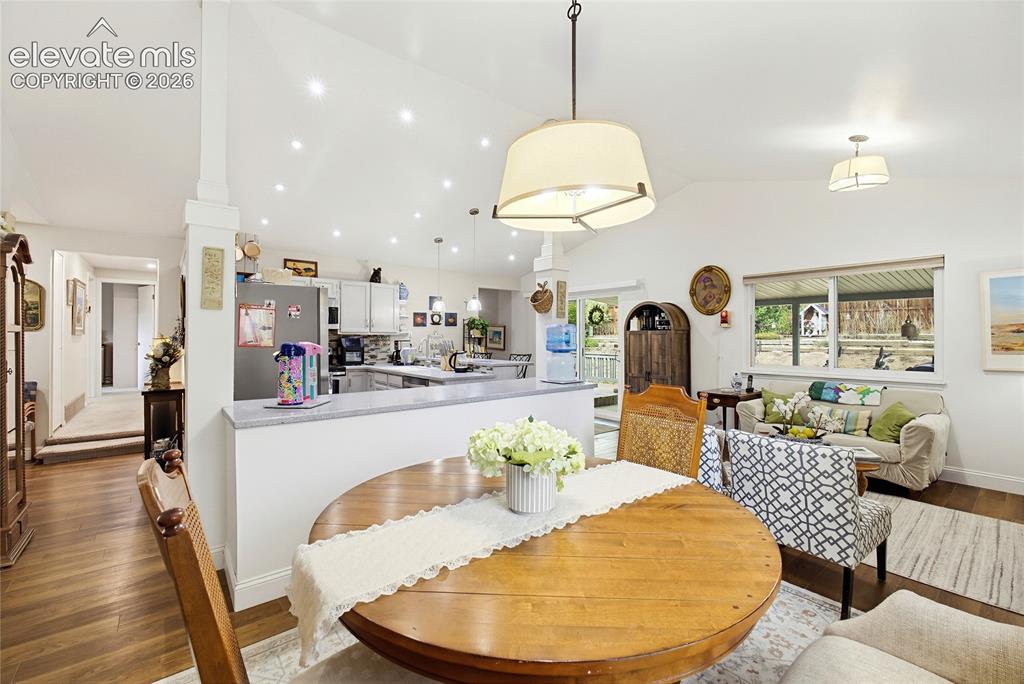Image 11 of 32: Vaulted white ceiling with recessed lighting, wood-finish flooring, white k