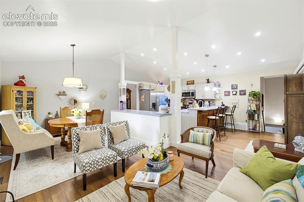 Image 12 of 32: Open-concept living area featuring wood-finish flooring, vaulted ceilings w
