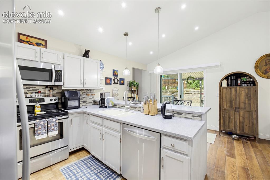 Image 16 of 32: Kitchen with vaulted ceiling, recessed lighting, white cabinetry, integrate
