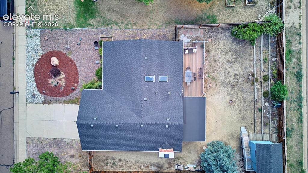 Image 2 of 32: Asphalt shingle roof with skylights, extensive wood deck, paved driveway, a