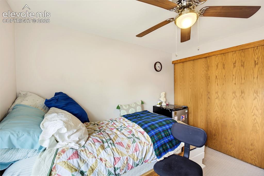Image 25 of 32: Wood-finish sliding closet doors, ceiling fan with integrated lighting, and