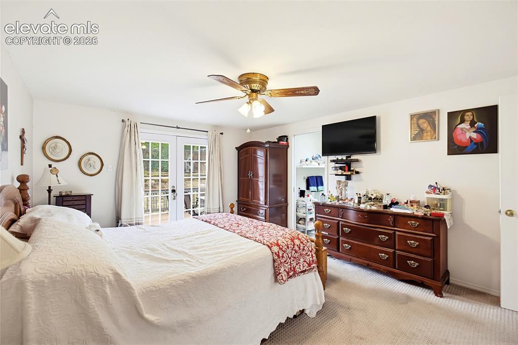 Image 27 of 32: Carpet flooring, ceiling fan with light fixture, and French doors leading t