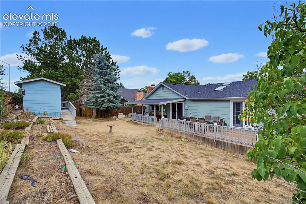 Image 5 of 32: Expansive backyard featuring a multi-level wood deck, mature trees, and a d