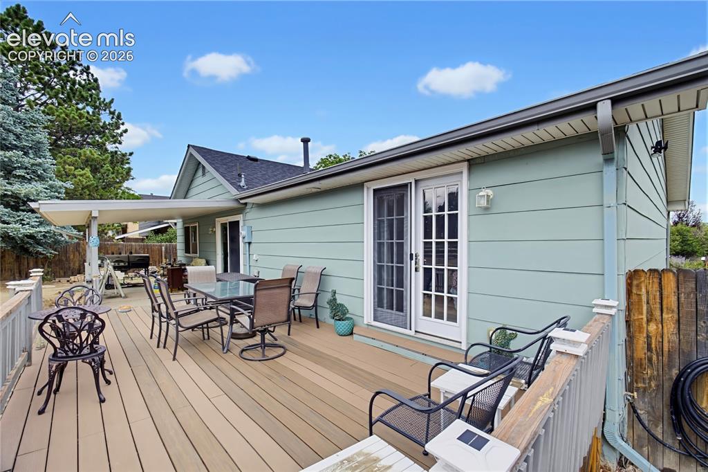Image 7 of 32: Rear exterior with a large composite deck, covered patio area, and sliding 