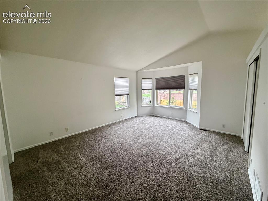 Image 14 of 50: Spacious room featuring vaulted ceilings, a bay window with multiple panes,