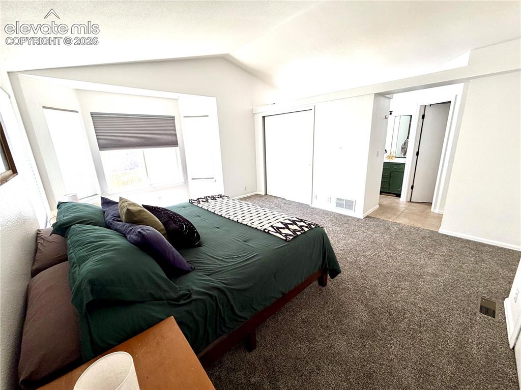 Image 15 of 50: Carpeted room featuring a vaulted ceiling and bay windows with privacy blin