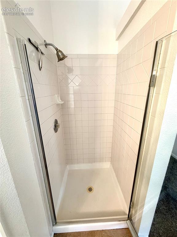 Image 18 of 50: Walk-in shower featuring white subway tile, decorative accent tiles, a sing