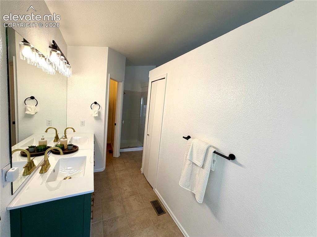 Image 19 of 50: Double vanity with a white countertop and deep green cabinetry