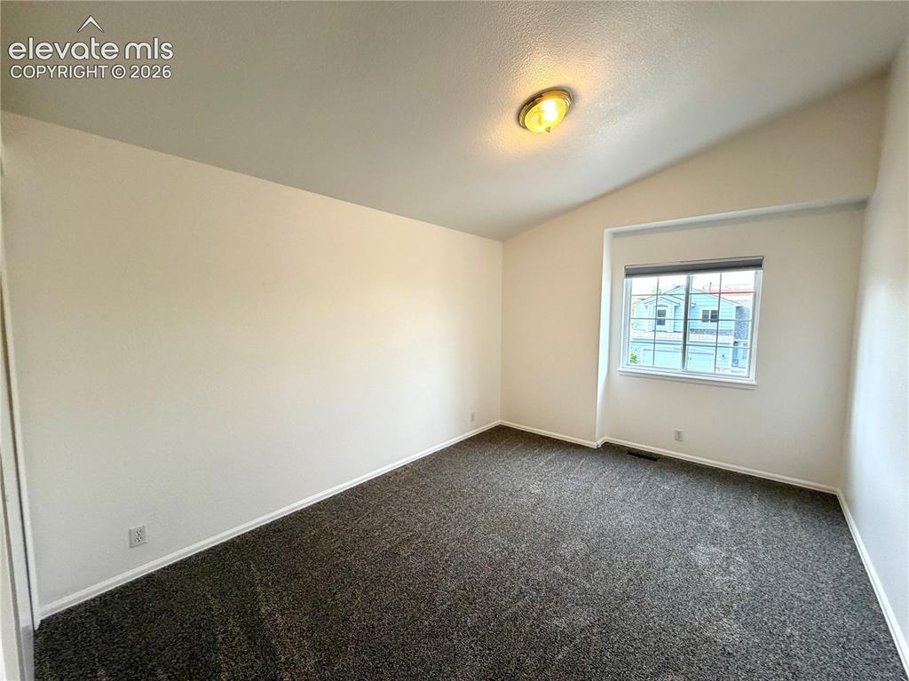 Image 22 of 50: Furniture removed. Spacious guest bedroom with vaulted ceiling and a single