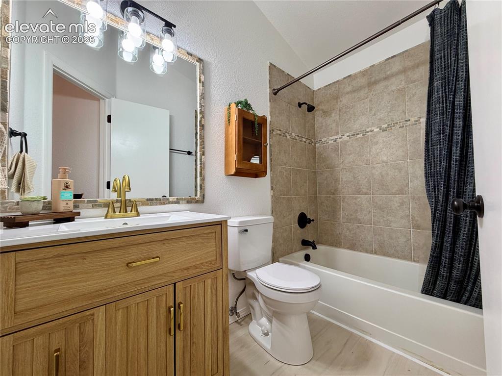 Image 23 of 50: Upstairs guest bathroom featuring a wood-finish vanity with gold-tone hardw