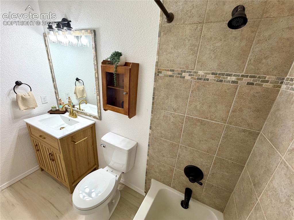 Image 24 of 50: Upstairs guest bathroom featuring a light wood-finish vanity with a white c