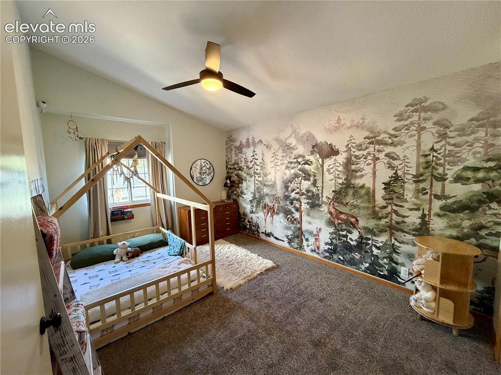 Image 25 of 50: Upstairs bedroom room featuring a vaulted ceiling with a ceiling fan
