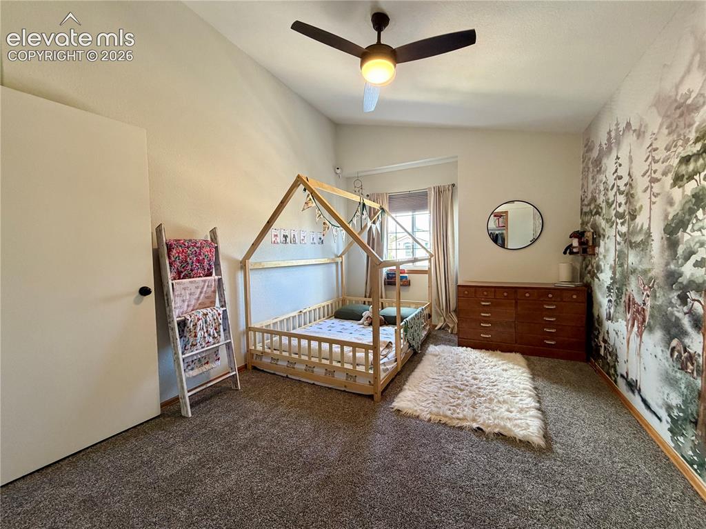 Image 27 of 50: Carpeted bedroom featuring a ceiling fan with integrated lighting, a wall m