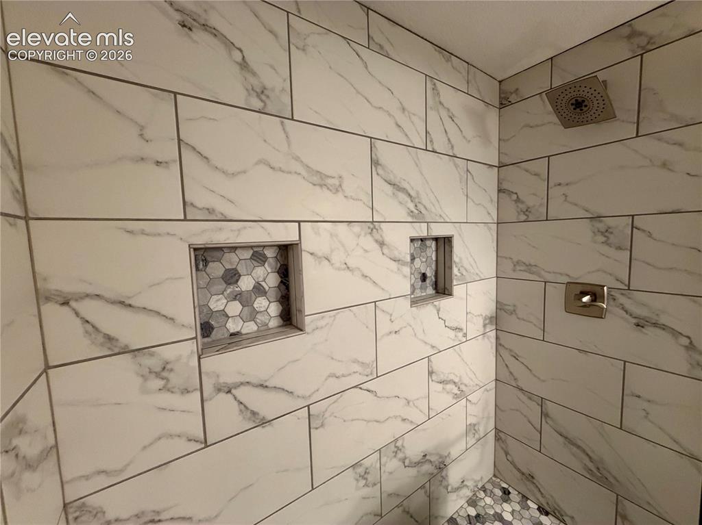 Image 33 of 50: Basement Bathroom-Shower featuring large format marble-look wall tiles, two