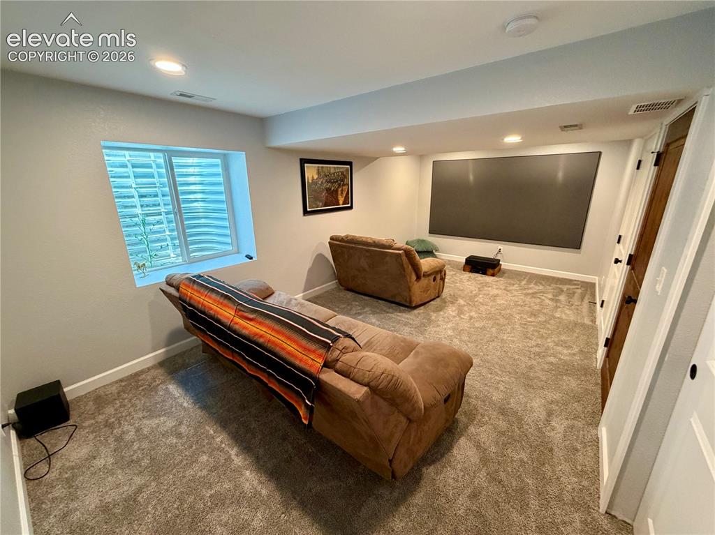 Image 35 of 50: Basement bedroom or media room featuring a large projection screen, recesse