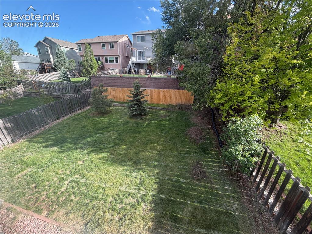 Image 40 of 50: Backyard featuring a large grass lawn, mature trees, and wood fencing