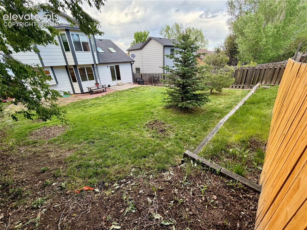 Image 47 of 50: Expansive backyard featuring a lush lawn, mature evergreen trees, and a con