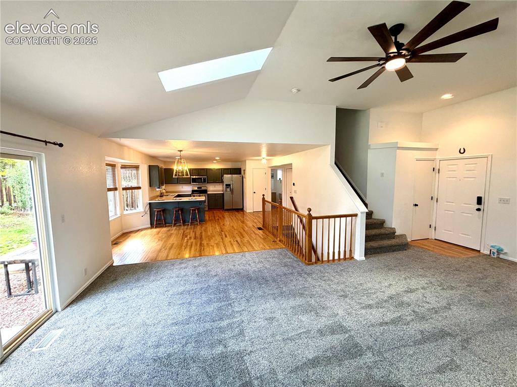 Image 6 of 50: Open-concept living area featuring a vaulted ceiling with a skylight, a lar