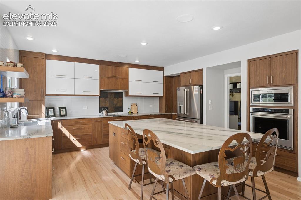 Image 10 of 50: Kitchen featuring wood-finish cabinetry with high-gloss white upper doors,