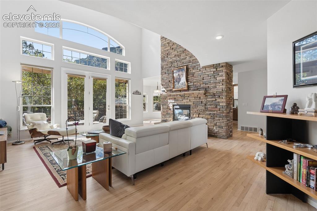 Image 6 of 50: Double-height living area featuring wood-finish flooring, a full-height sto