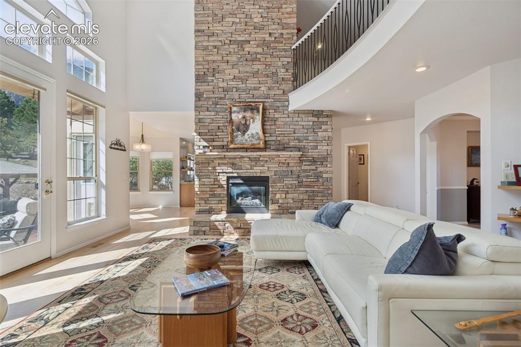 Image 8 of 50: Two-story living area featuring a full-height stone-veneer fireplace, vault