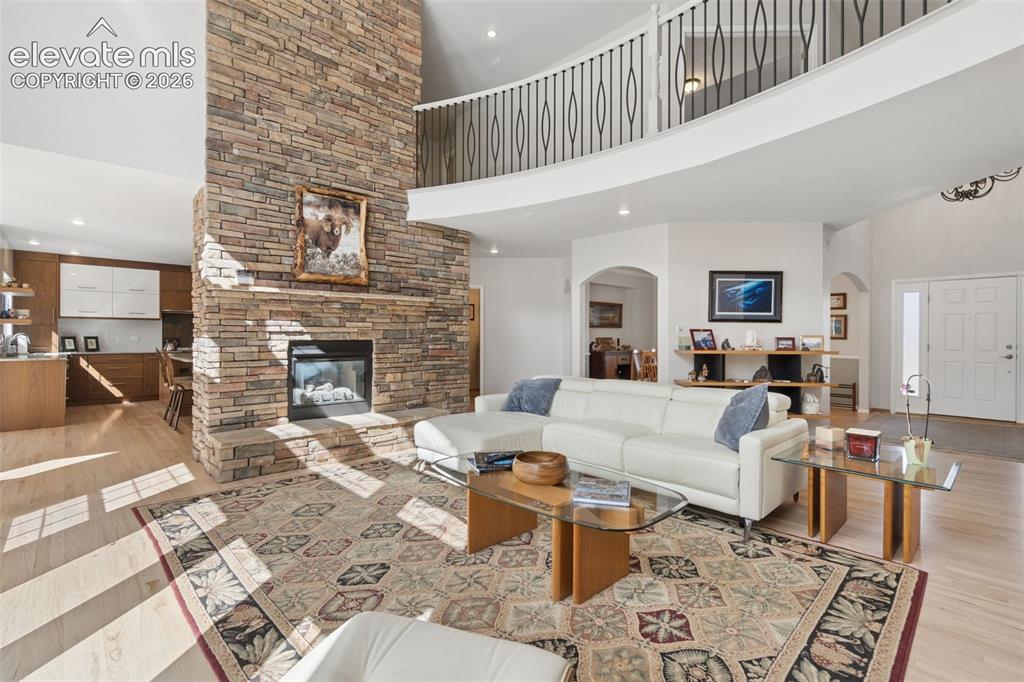 Image 9 of 50: Two-story interior space featuring a floor-to-ceiling stone-veneer fireplac