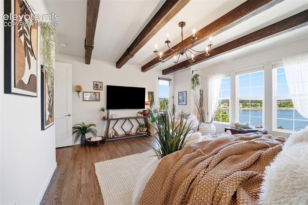 Image 20 of 50: Main-level primary with wood ceiling beams and chandelier