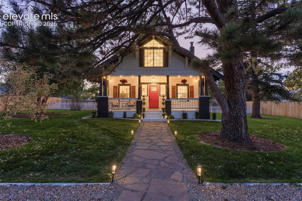 Image 1 of 43: Charming home exterior featuring a red front door, covered porch, and white
