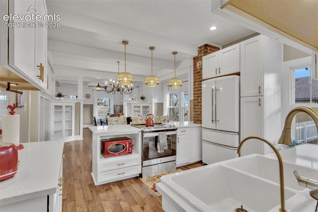 Image 13 of 43: Spacious kitchen featuring white cabinetry, light countertops, wood-finish