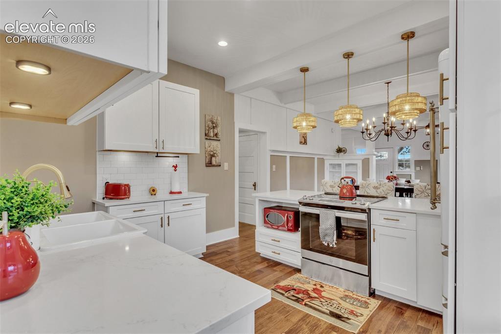 Image 14 of 43: Kitchen featuring white cabinetry, quartz countertops, subway tile backspla