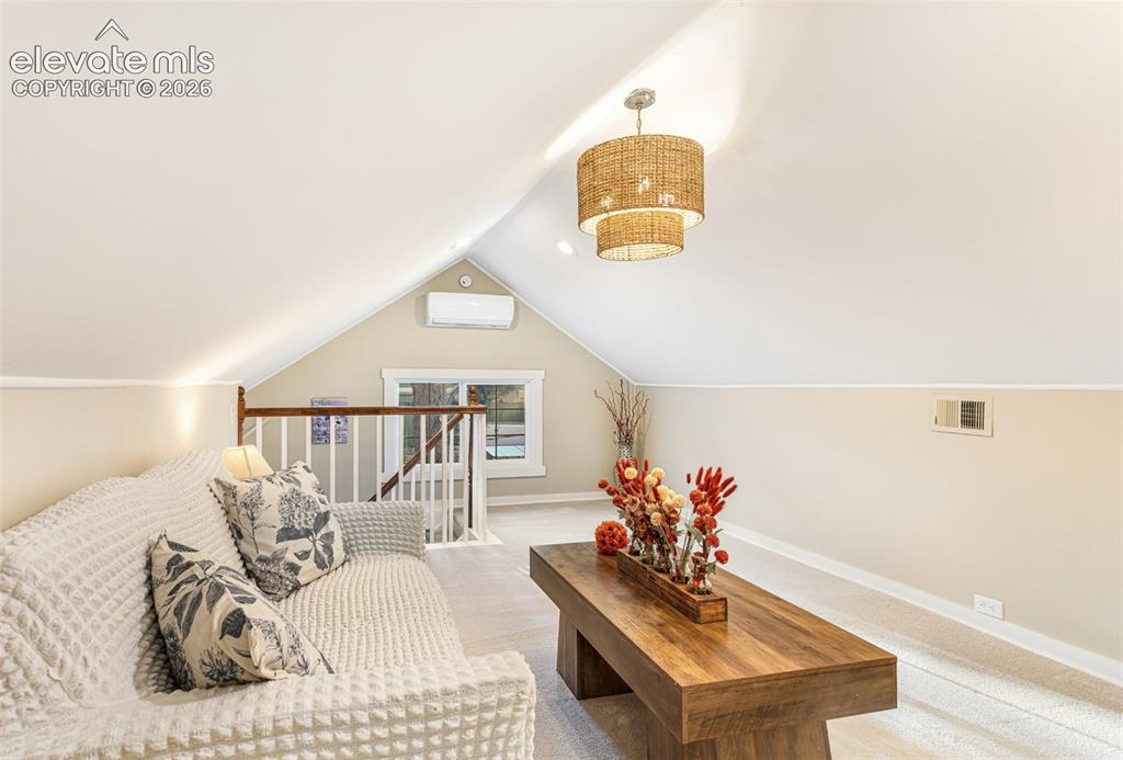 Image 18 of 43: Vaulted ceiling loft space featuring a tiered woven chandelier, wall-mounte