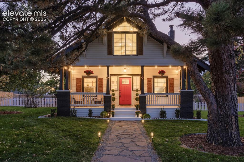 Image 2 of 43: Charming exterior featuring a prominent red entry door, a covered front por