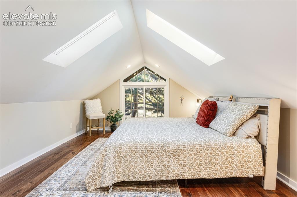 Image 24 of 43: Vaulted ceiling bedroom featuring two skylights, a large picture window, re