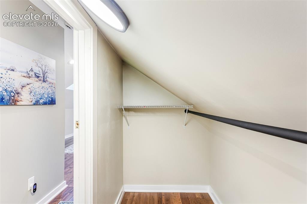 Image 26 of 43: Sloped ceiling closet featuring wood-finish flooring, a metal hanging rod,