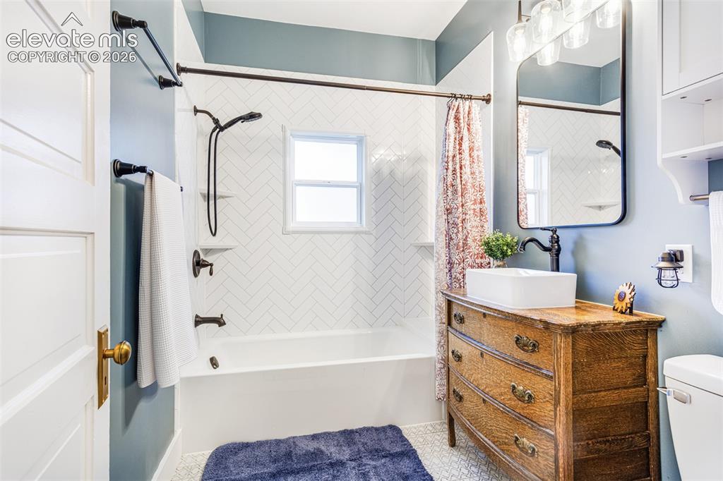Image 29 of 43: Bathroom featuring a white bathtub, herringbone pattern tile surround, blac