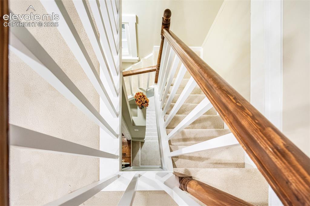 Image 38 of 43: Carpeted staircase featuring a wood-finish handrail and white balusters
