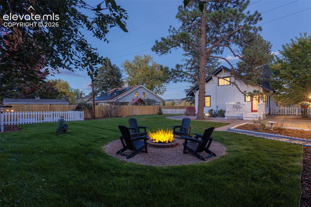 Image 4 of 43: Manicured lawn featuring a gravel fire pit area with Adirondack chairs