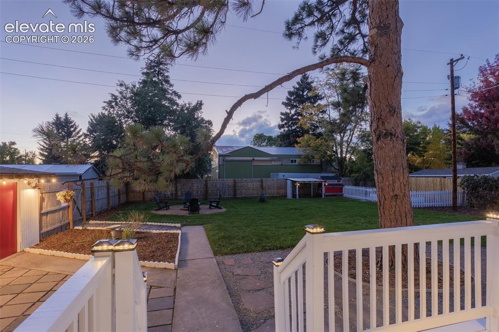 Image 41 of 43: Expansive backyard featuring a manicured lawn, dedicated fire pit area, pav