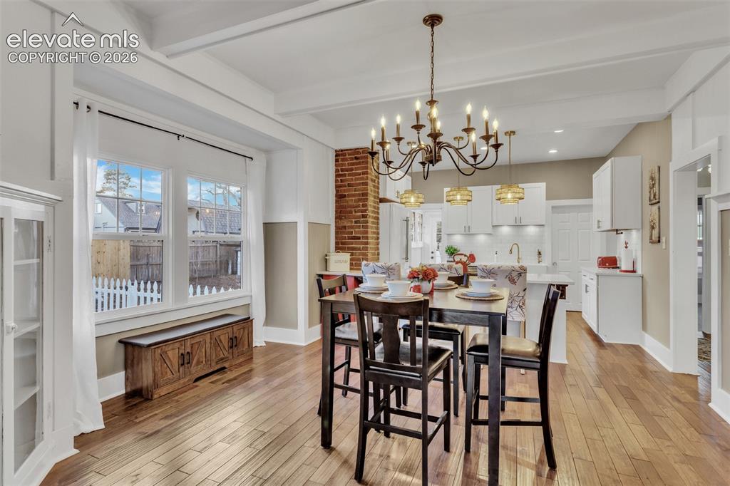 Image 9 of 43: Dining area featuring a prominent chandelier, wood-finish flooring, exposed