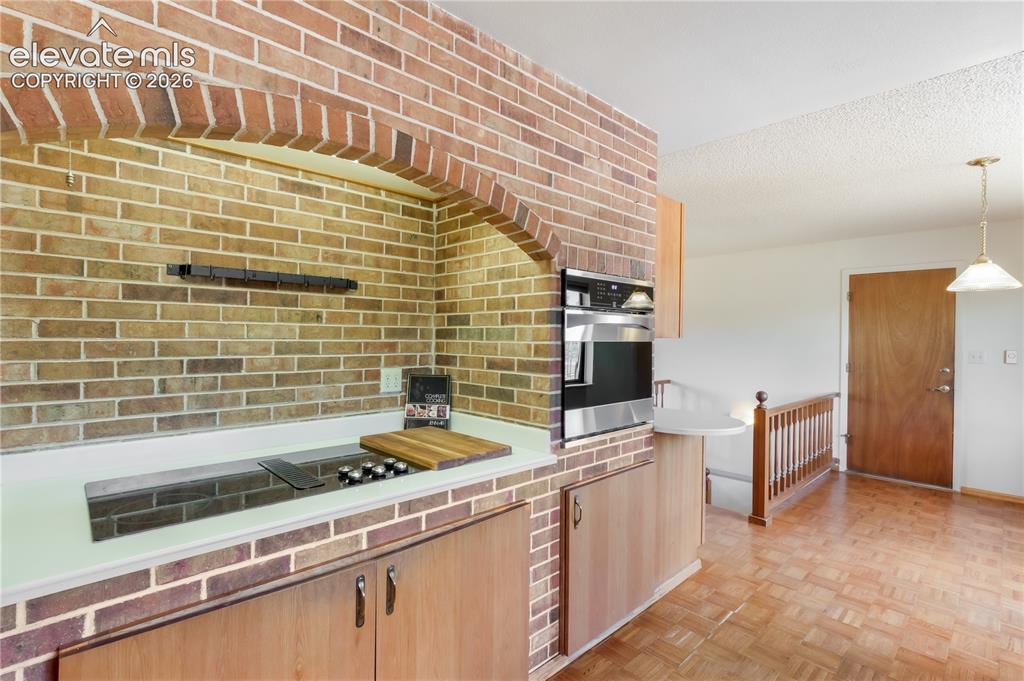 Image 12 of 47: Kitchen off the entry with brick around cooktop