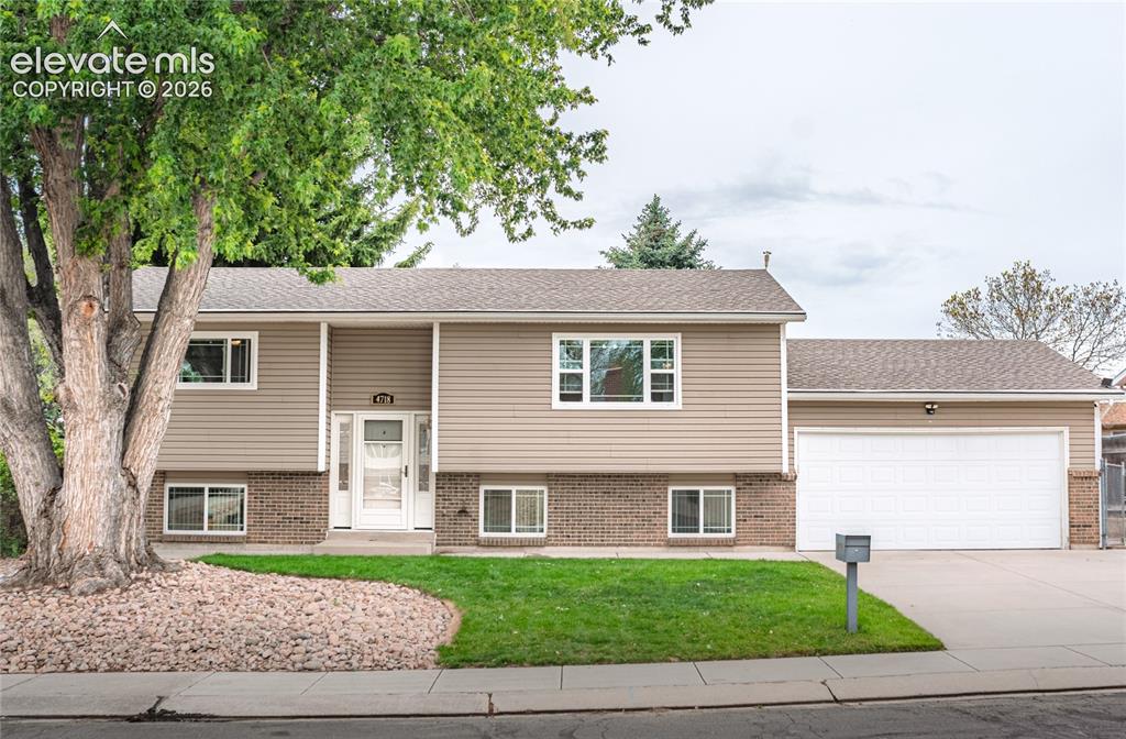 Image 1 of 34: Split-level residence featuring tan horizontal siding and brick accents