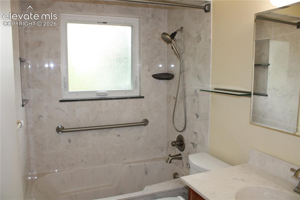 Image 16 of 34: Bathroom featuring a bathtub with a shower, a vanity, and a window