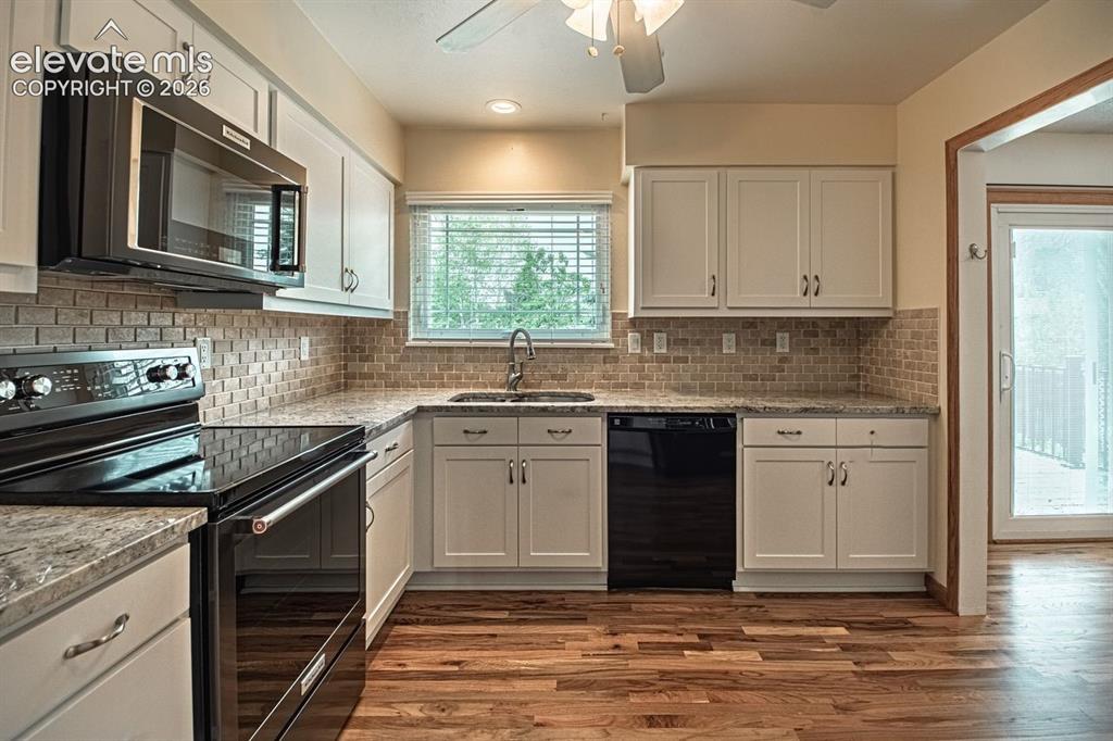 Image 2 of 34: Kitchen featuring white cabinetry, a tile backsplash, hardwood flooring, an