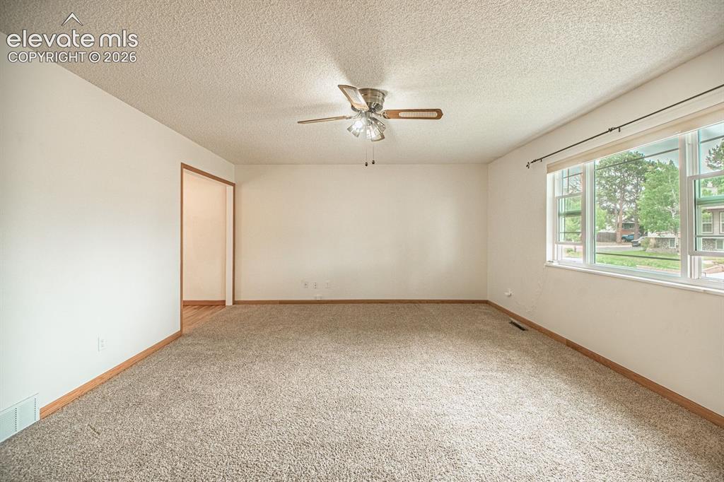 Image 20 of 34: Spacious living area featuring neutral wall tones, a ceiling fan with integ