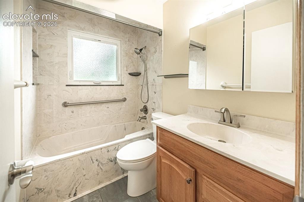 Image 22 of 34: Bathroom featuring a built-in bathtub with a marble surround, window, vanit