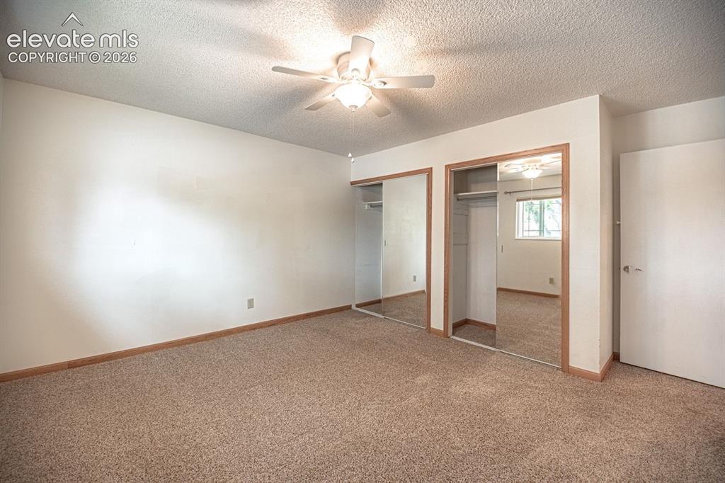 Image 23 of 34: Carpeted room featuring a ceiling fan with light fixture, two mirrored slid