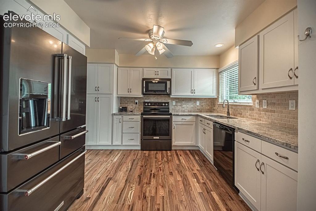 Image 3 of 34: Kitchen featuring hardwood flooring, white cabinetry, a neutral subway tile
